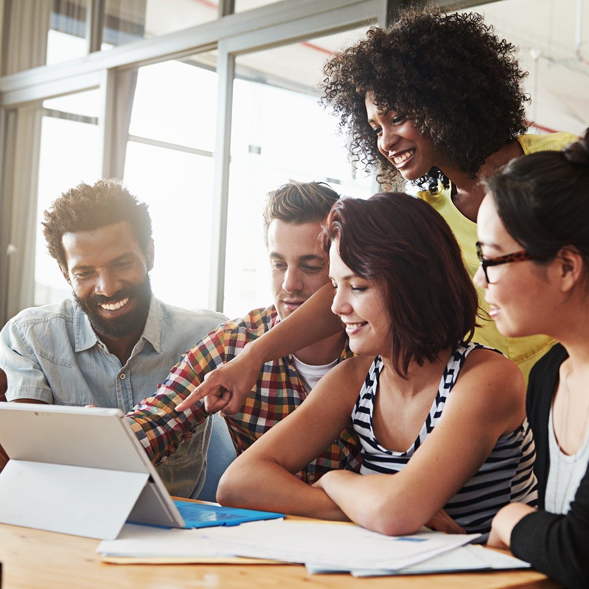 coworkers stand behind smart device reviewing work